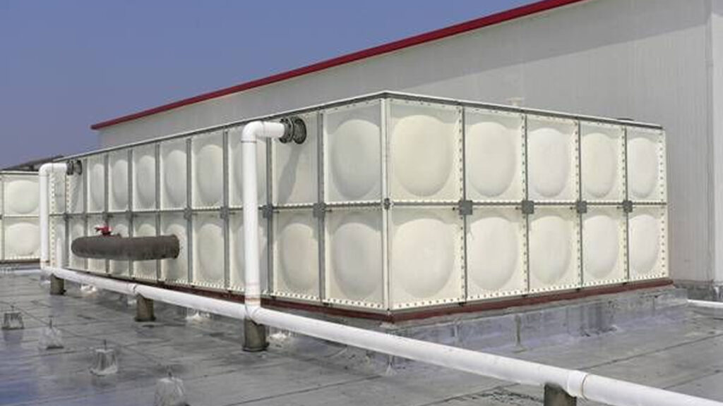 water tank installation on a commercial building rooftop, featuring modular panel construction for domestic and industrial water storage applications with connected piping infrastructure.