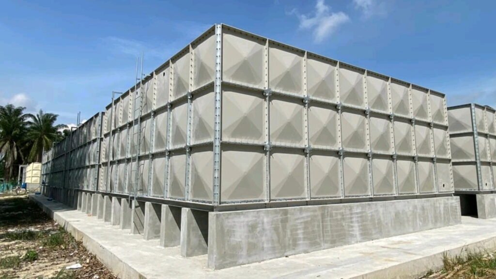 Large FRP panel water storage tank installed on a reinforced concrete base, featuring modular fiberglass panels with galvanized steel supports, designed for industrial and municipal water storage applications.