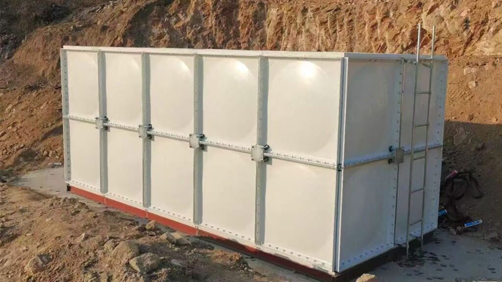 Rectangular FRP sectional water tank installed at a construction site, equipped with an access ladder and galvanized steel framework, providing durable and corrosion-resistant water storage.