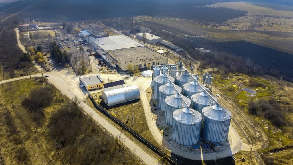 erial view of an industrial fuel storage facility with large metal storage tanks surrounded by agricultural fields.